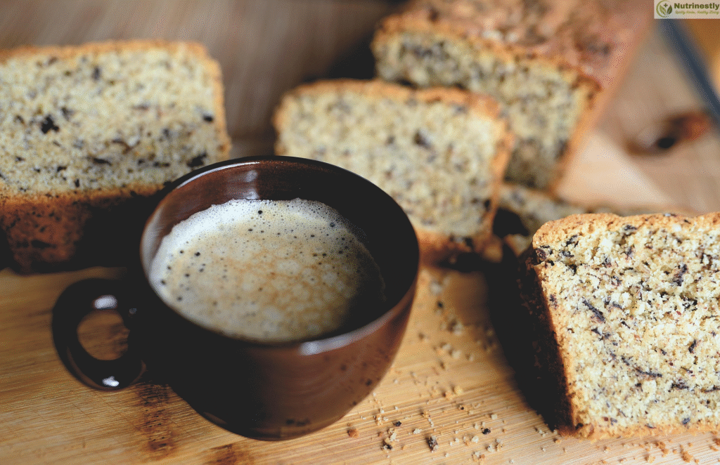 A cup of freshly brewed coffee with slices of coffee-flavored cake on a wooden board, showcasing a moist texture and nutty crumb.